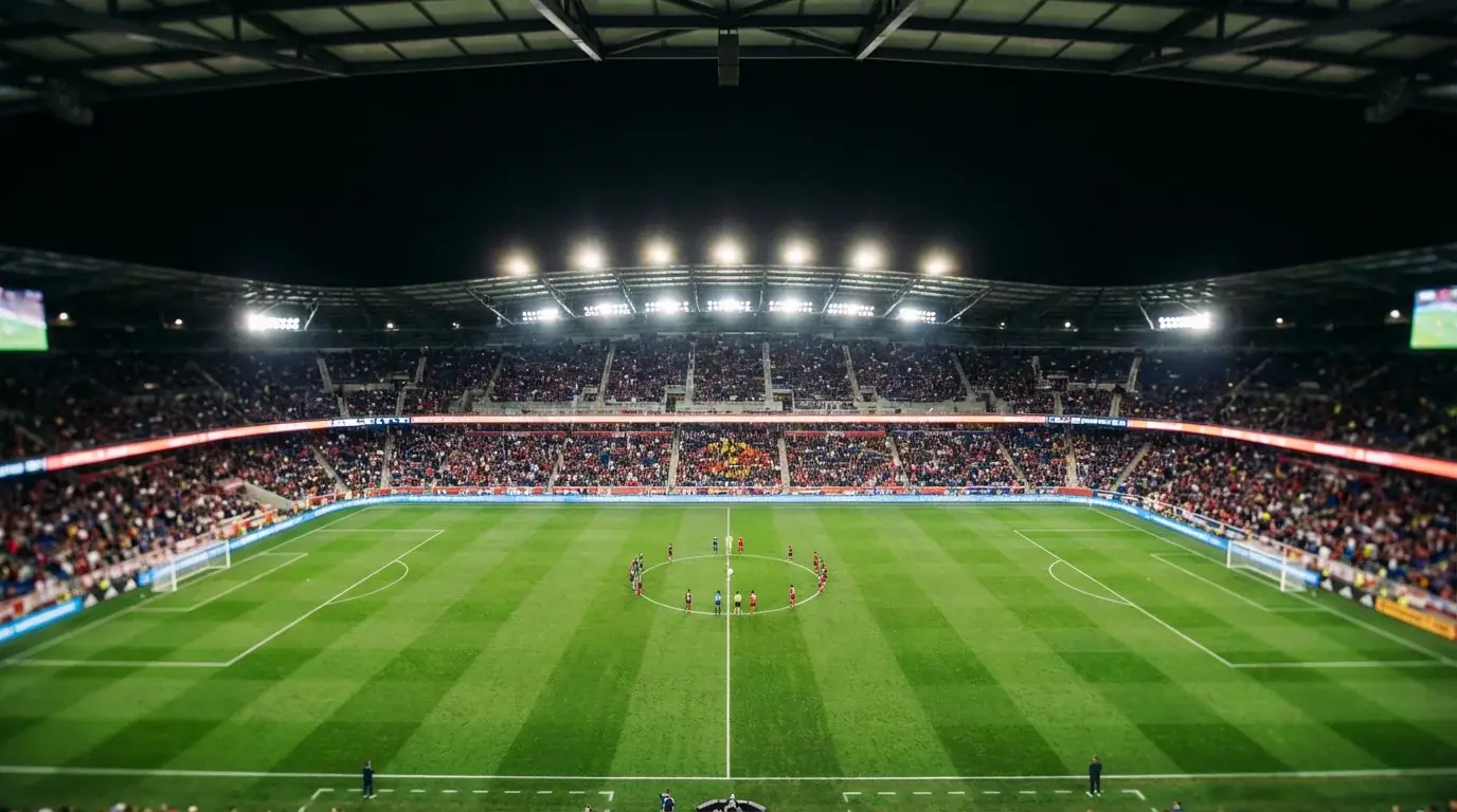 Páirc sacair faoi shoilse geala oíche le himreoirí ag imirt ar fhéar glas